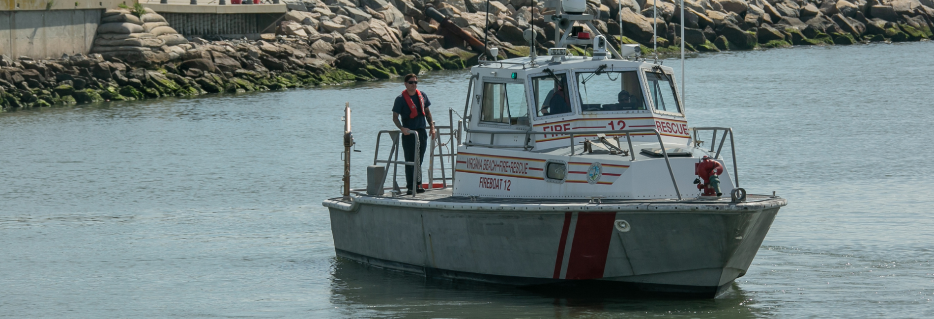 Fire boat traveling through Rudee Inlet on sunny day