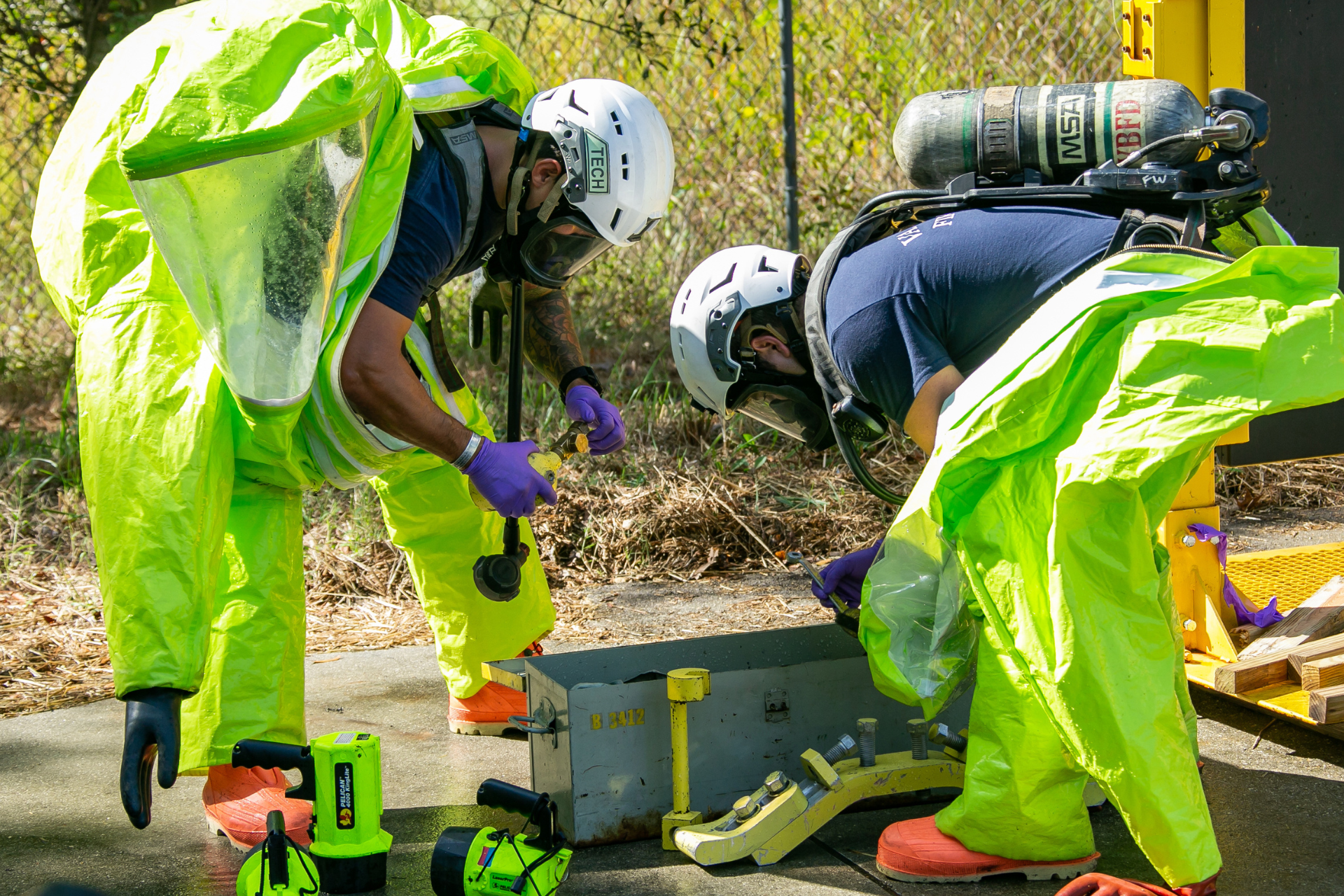Two hazmat team members putting on gear