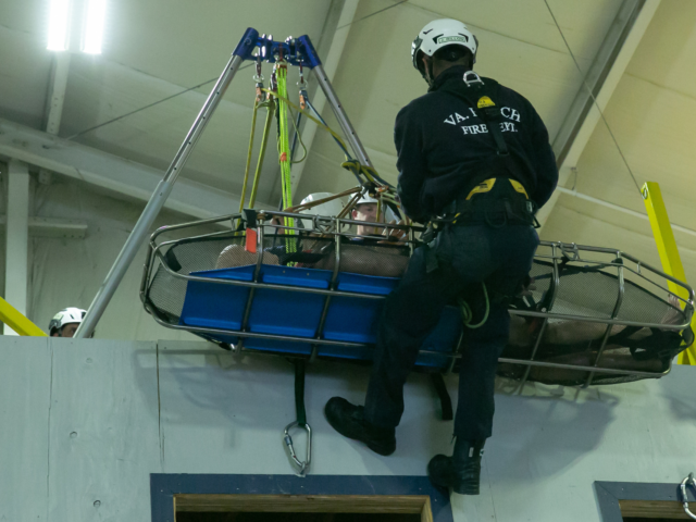 Firefighter practicing urban search and rescue with stretcher and climbing gear