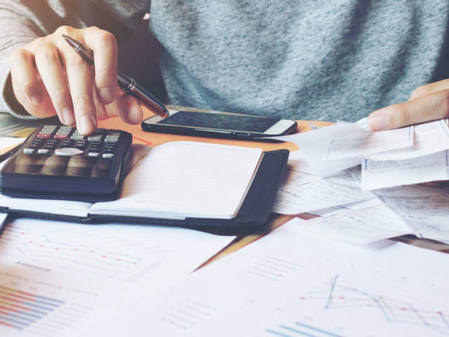 Person using calculator to add the stack of bills on the table Payment Assistance and Pay My Bill Header