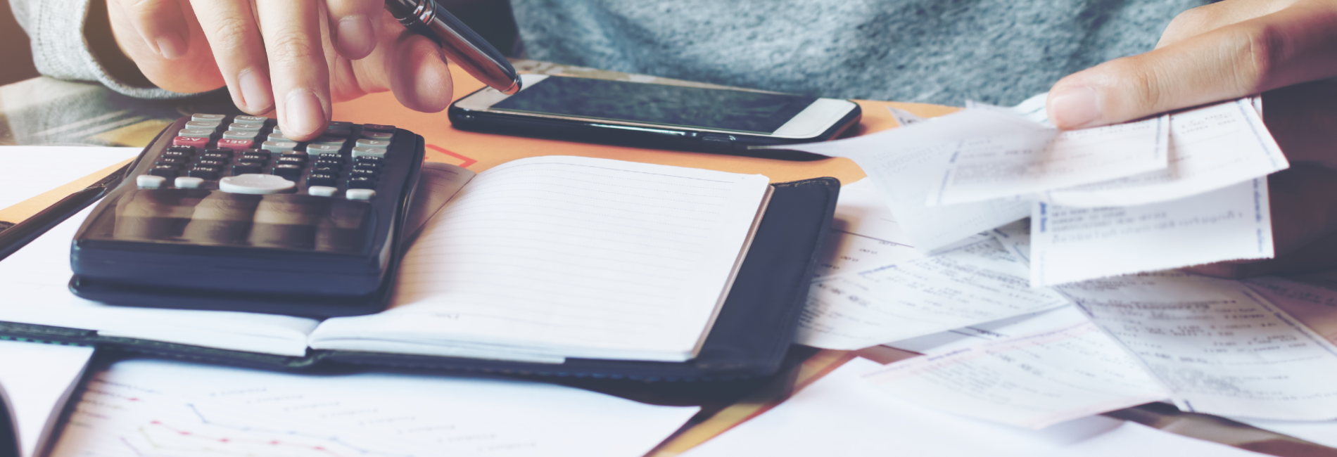 Person using calculator to add the stack of bills on the table Payment Assistance and Pay My Bill Header