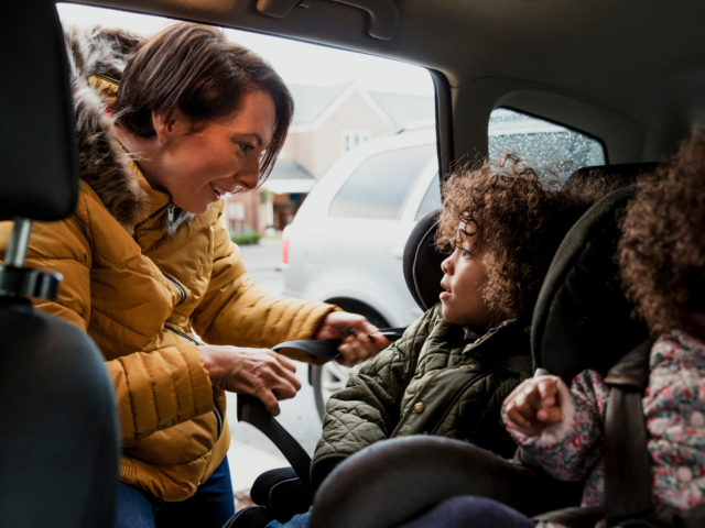 Woman securing child in car seat