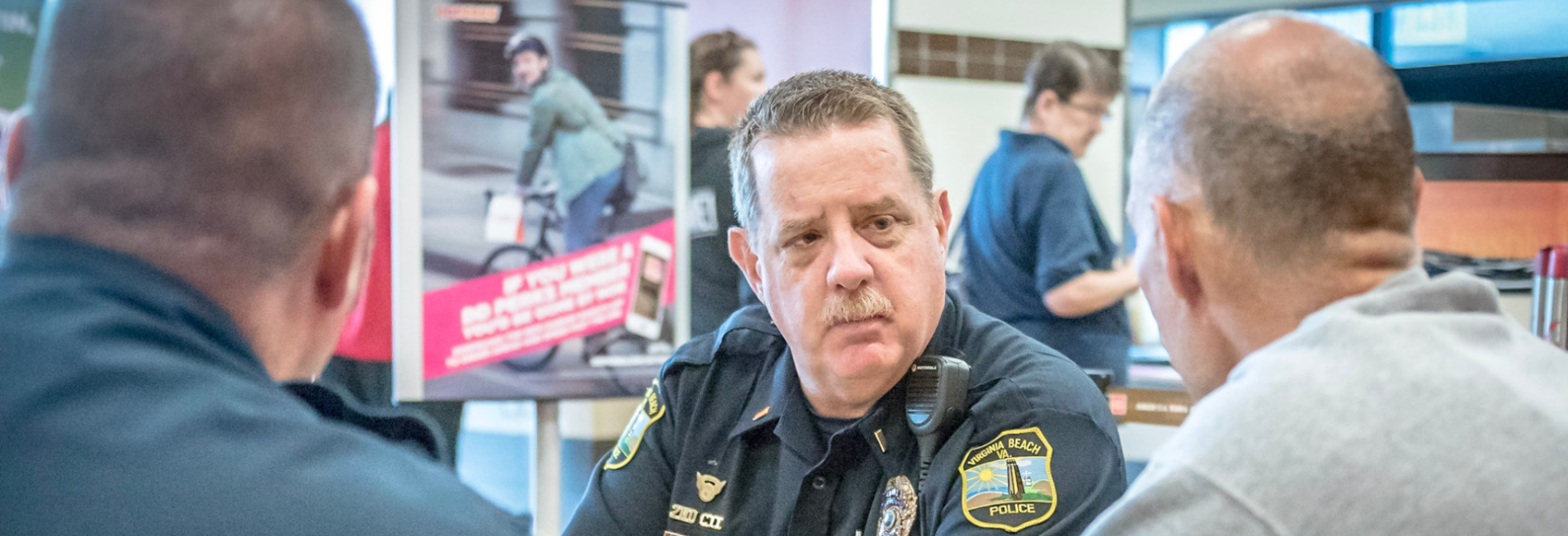 Police officer listens to two residents at Coffee With a Cop event