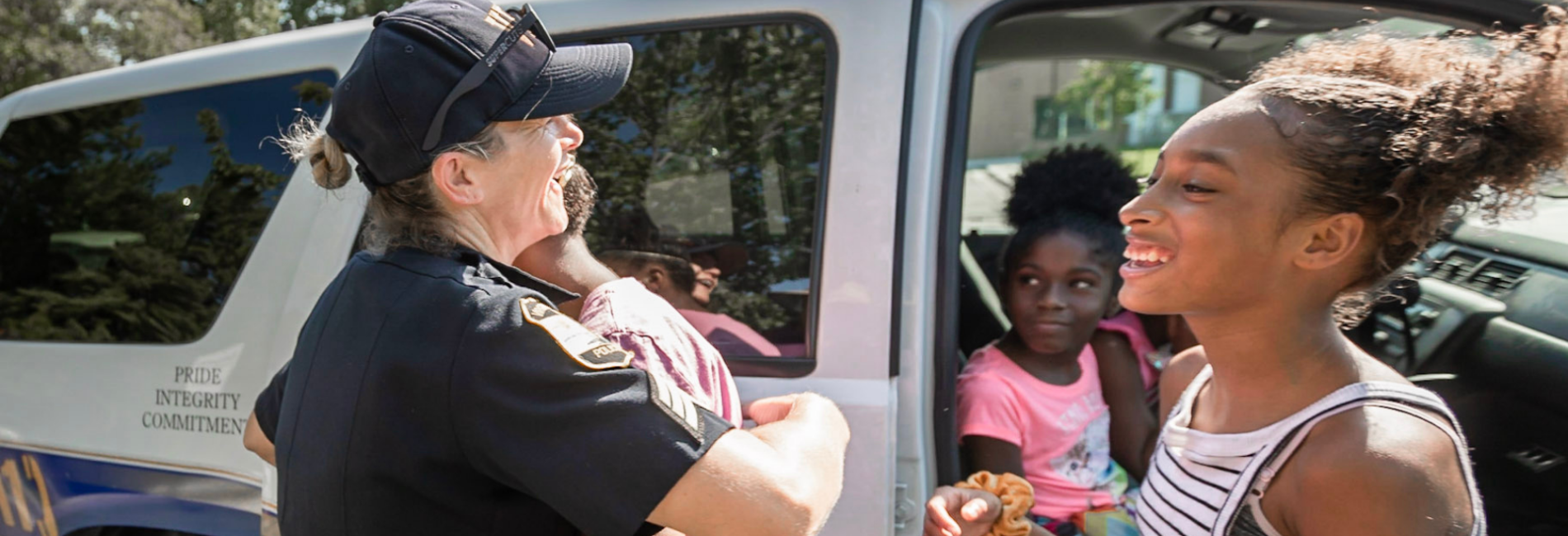Female police officer getting a hug from a young girl during community event