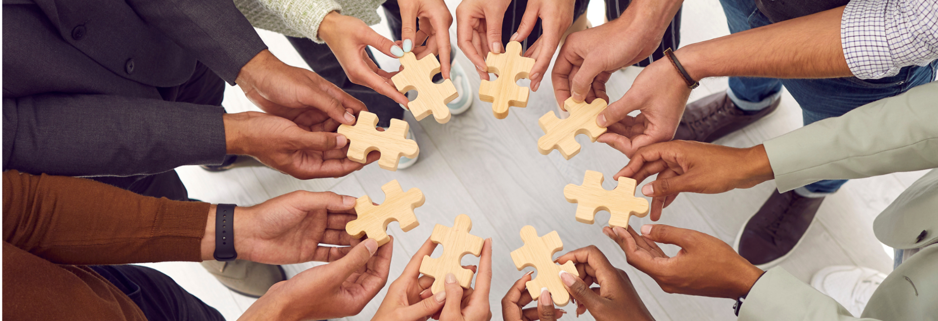 Group of individuls in circle holding puzzle pieces together